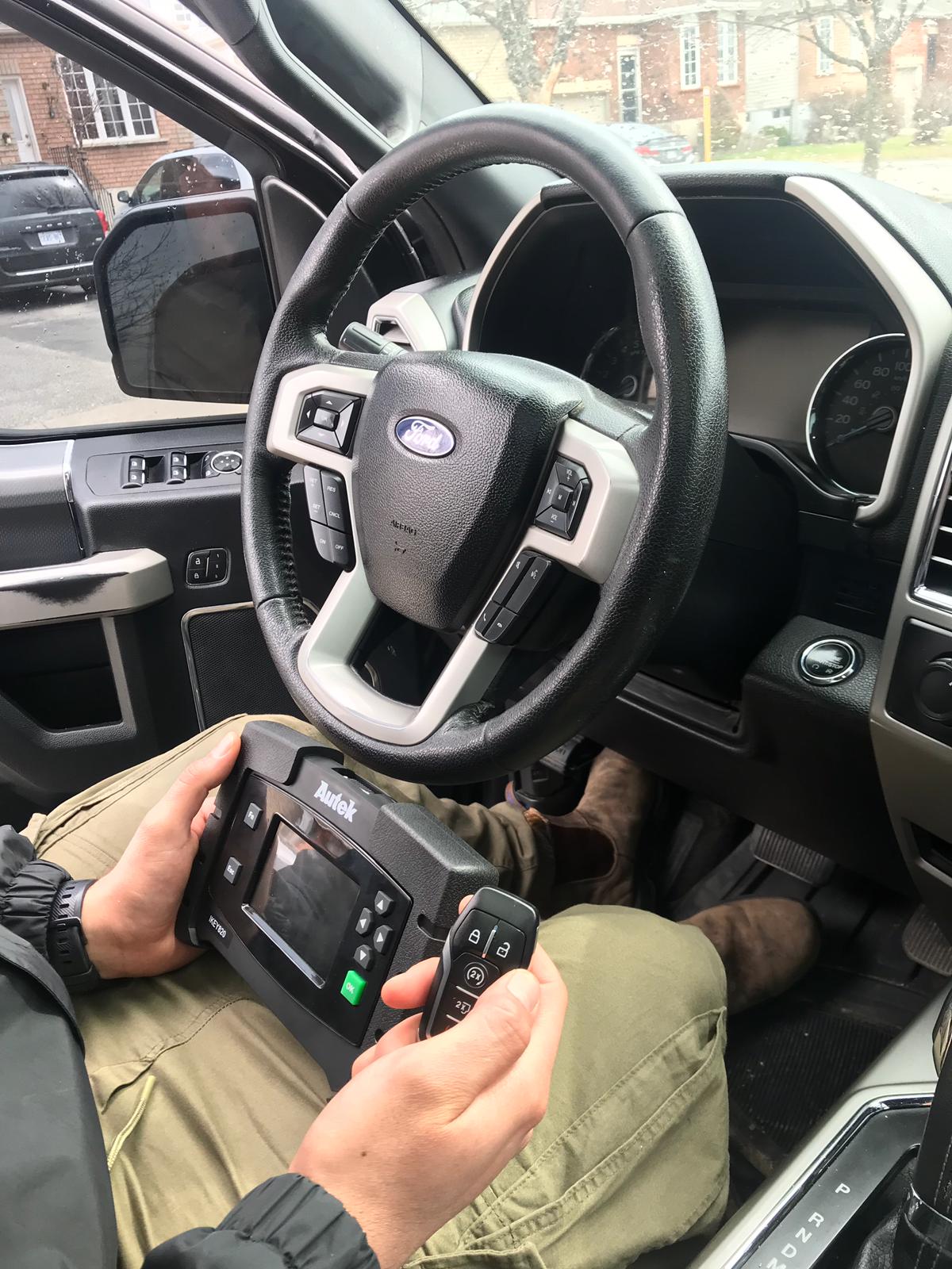 A locksmith technician programming a new car key fob with a diagnostic tool.