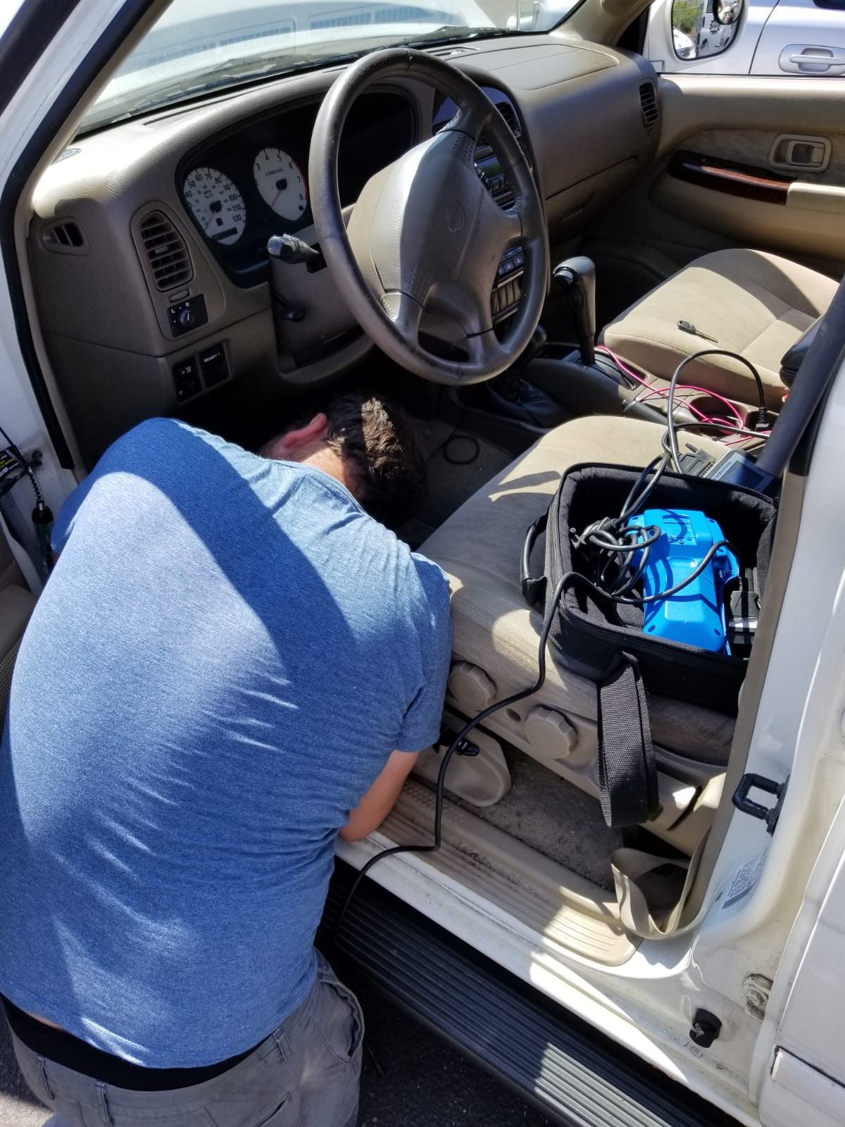A locksmith technician programming a new car key fob with a diagnostic tool.